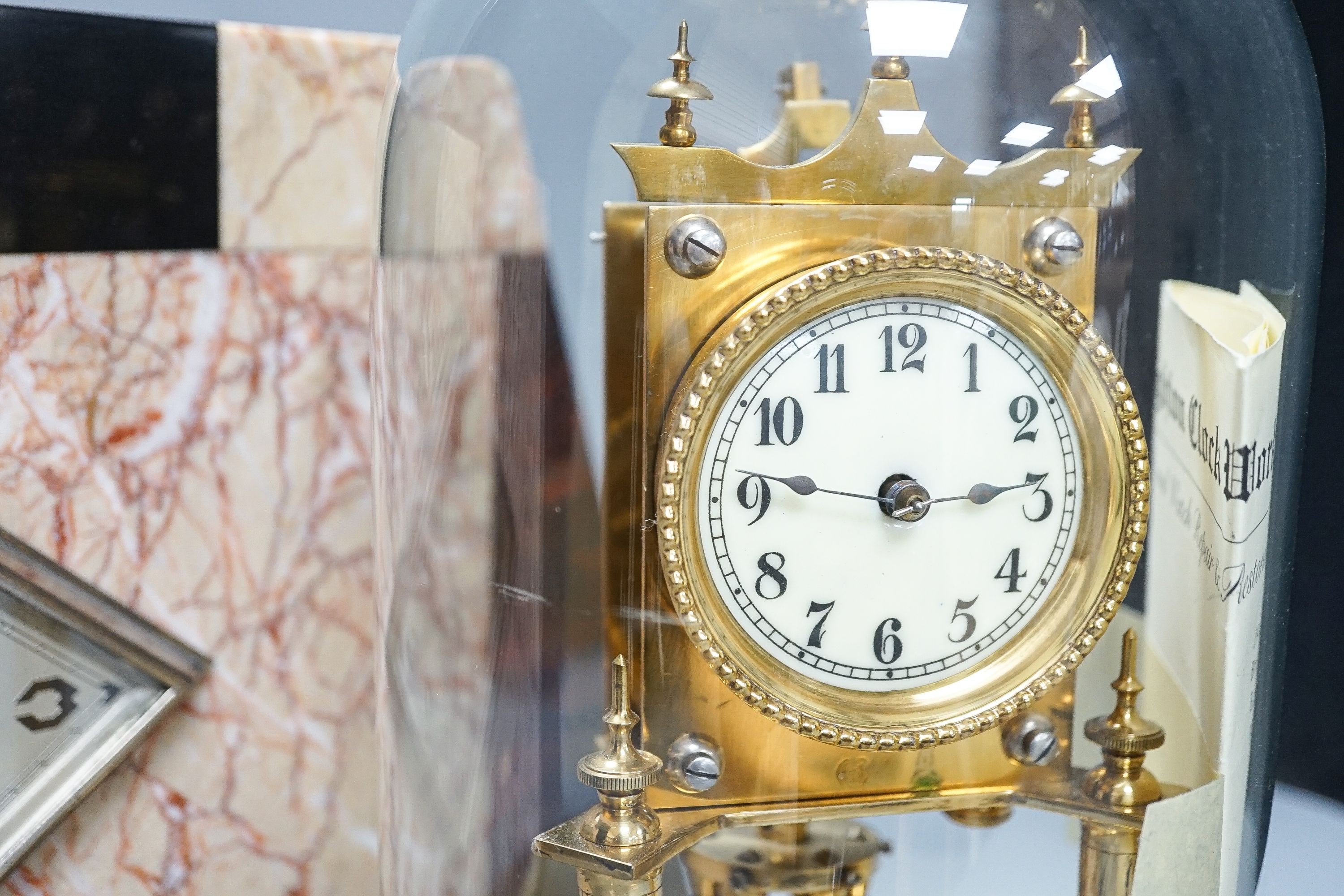An Art Deco rouge marble mantel timepiece, 45cm wide, quartz movement replacement and a brass anniversary clock under glass dome